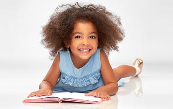 Happy young girl learning to read