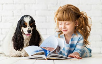 Four-year-old girl learning how to read with her puppy